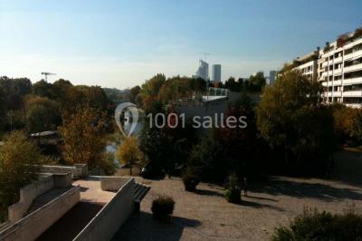 Salle vide avec sol clair, murs verts et blancs, grandes fenêtres, éclairage au plafond et mobilier minimal.