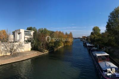 Salle vide avec sol clair, murs verts et blancs, grandes fenêtres, éclairage au plafond et mobilier minimal.