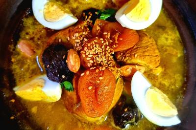 Plat de tajine avec des morceaux d'abricots secs, pruneaux, amandes, œufs durs et graines de sésame dans une sauce.