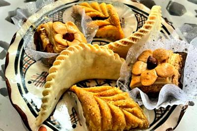 Assortiment de pâtisseries orientales sur une assiette décorative, comprenant cornes de gazelle et gâteaux aux amandes.