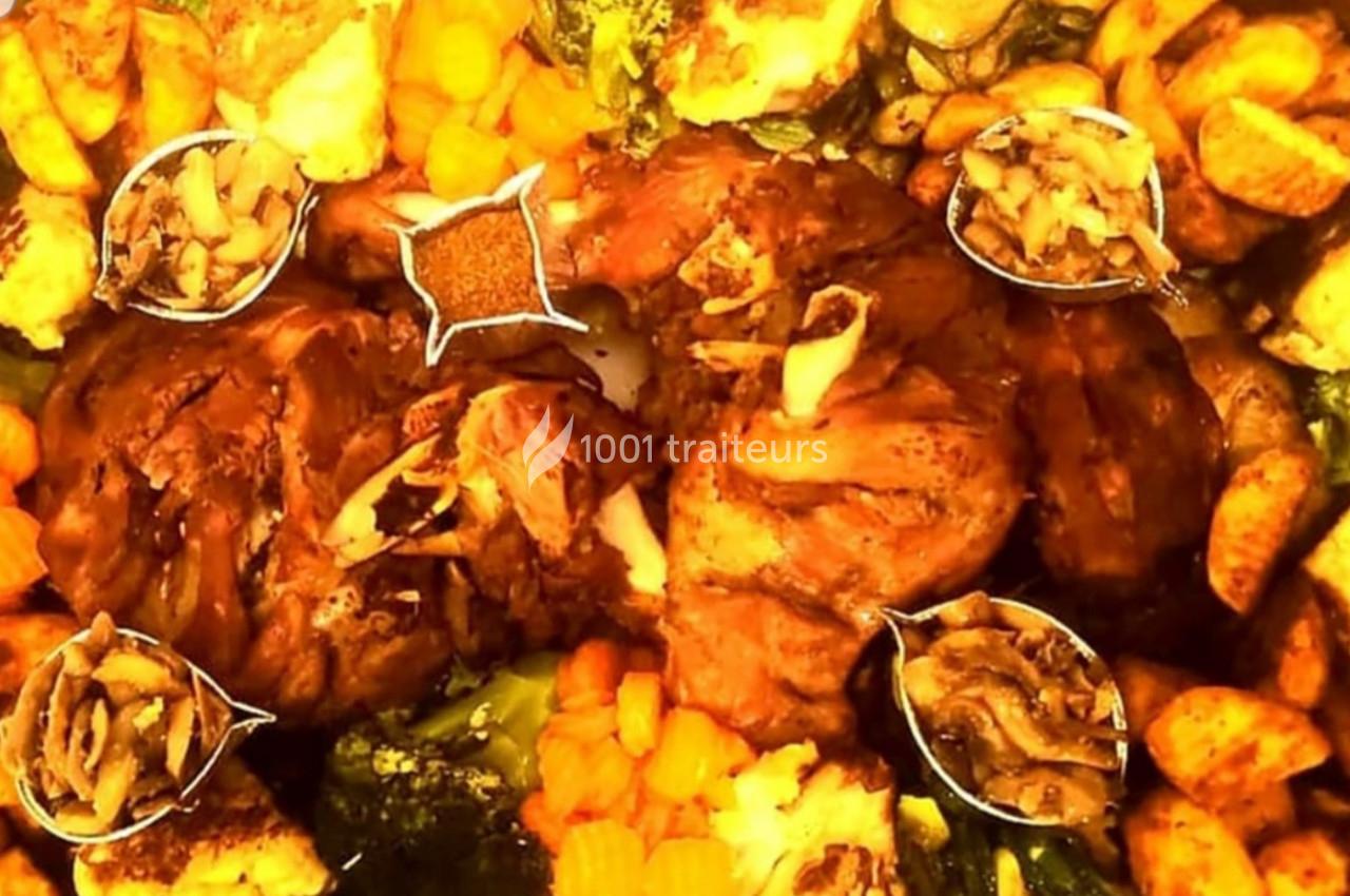 Plat de viande rôtie entouré de légumes variés, pommes de terre, carottes et brocolis, avec des condiments disposés autour.