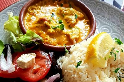 Assiette garnie de légumes variés, morceaux de viande et sauce rouge au centre, présentée sur un lit de salade.