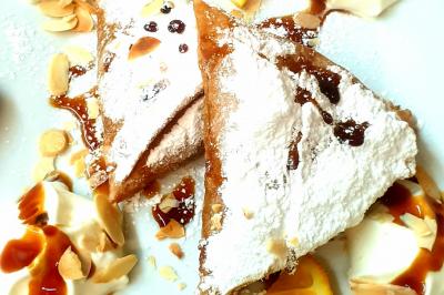 Assiette garnie de légumes variés, morceaux de viande et sauce rouge au centre, présentée sur un lit de salade.