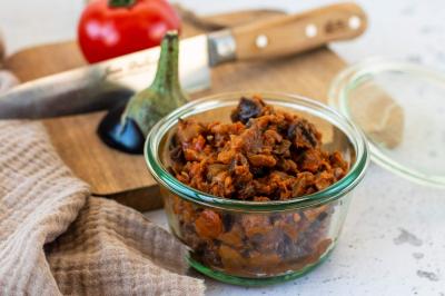 Assiette garnie de légumes variés, morceaux de viande et sauce rouge au centre, présentée sur un lit de salade.