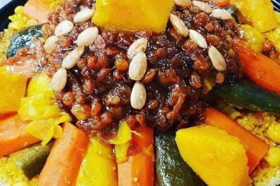 Assiette garnie de légumes variés, morceaux de viande et sauce rouge au centre, présentée sur un lit de salade.