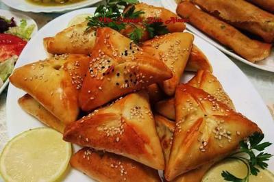 Assiette garnie de légumes variés, morceaux de viande et sauce rouge au centre, présentée sur un lit de salade.
