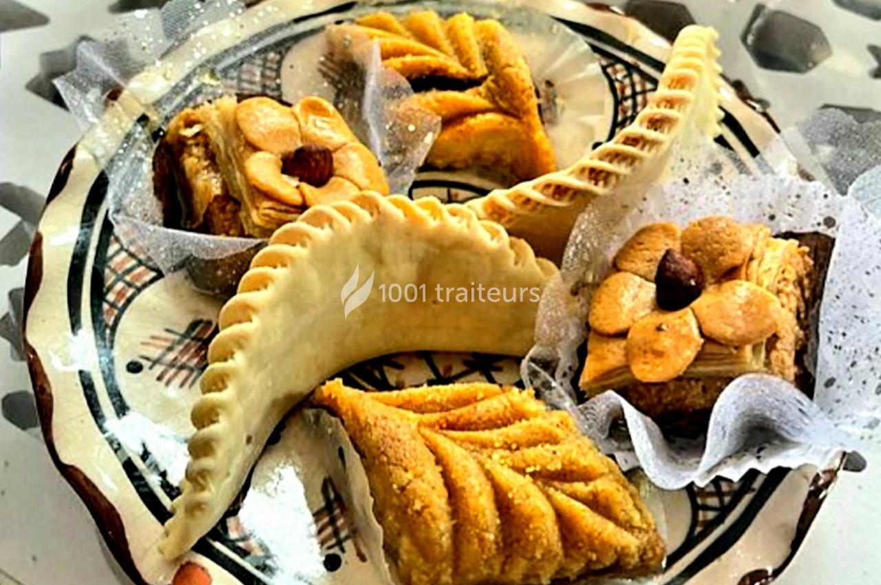 Assortiment de pâtisseries orientales sur une assiette décorative, comprenant cornes de gazelle et gâteaux aux amandes.