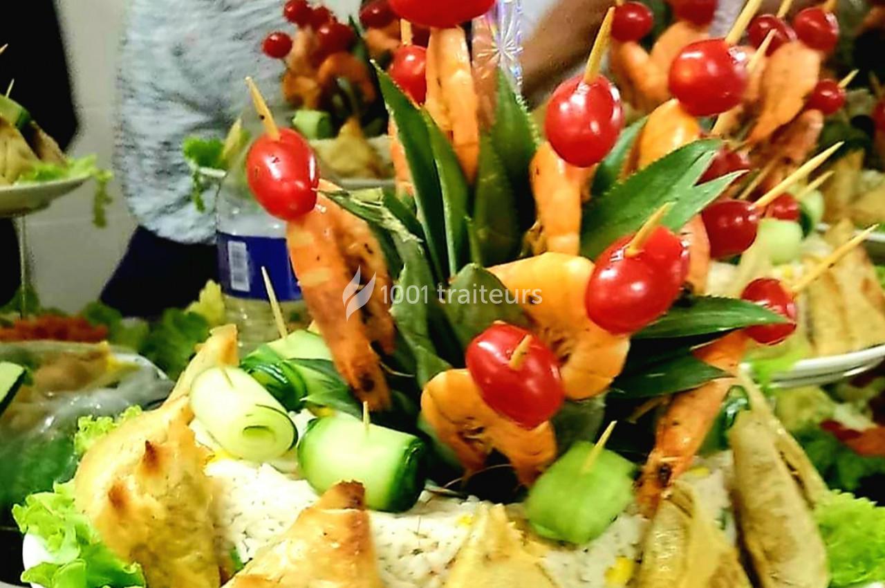 Plateau décoratif avec brochettes de crevettes, tomates cerises, feuilles vertes et rouleaux de concombre sur un lit de riz.