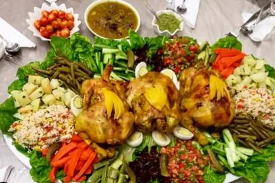 Assiette garnie de légumes variés, morceaux de viande et sauce rouge au centre, présentée sur un lit de salade.