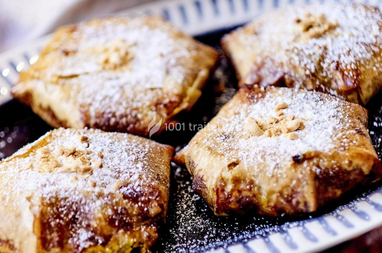 Pâtisseries dorées en forme carrée, saupoudrées de sucre glace et garnies d'une décoration centrale.