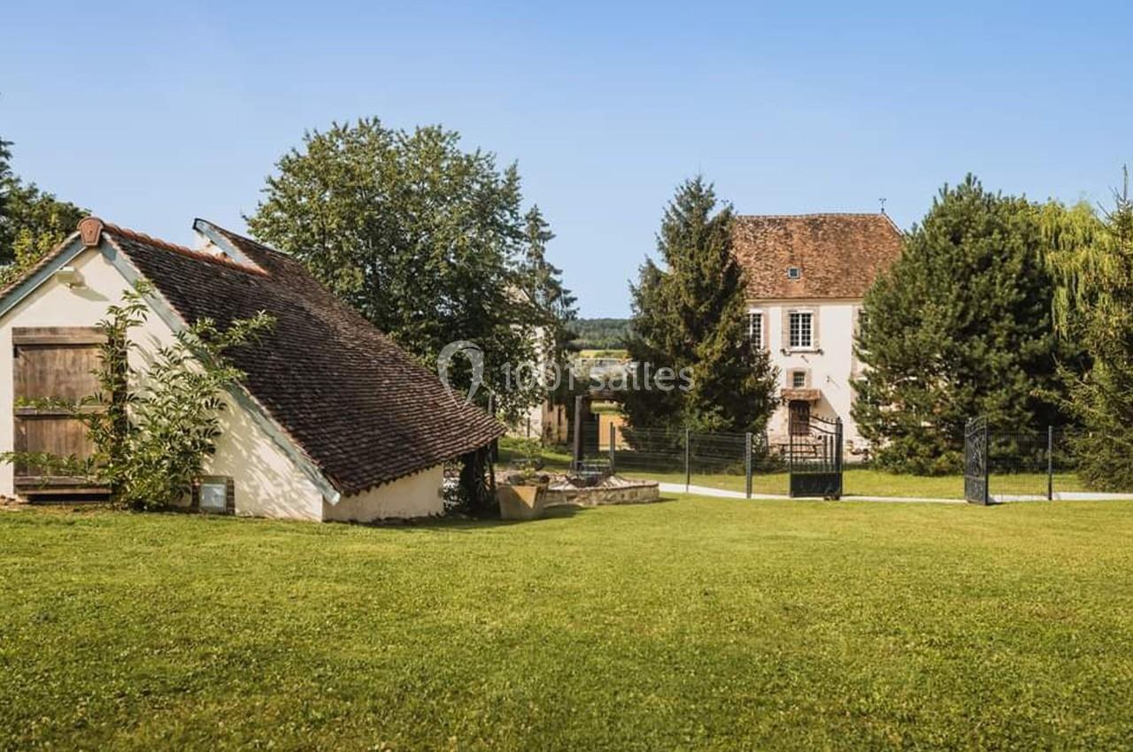 Deux maisons traditionnelles entourées de pelouses et d'arbres sous un ciel bleu clair.