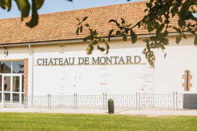 Lit simple avec une tête de lit en bois, couvert d'une couverture à motifs tropicaux, dans une chambre lumineuse.