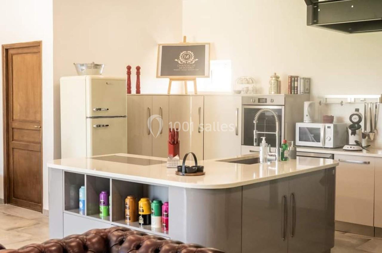 Cuisine moderne avec îlot central, réfrigérateur rétro, évier intégré, électroménagers et étagères ouvertes.