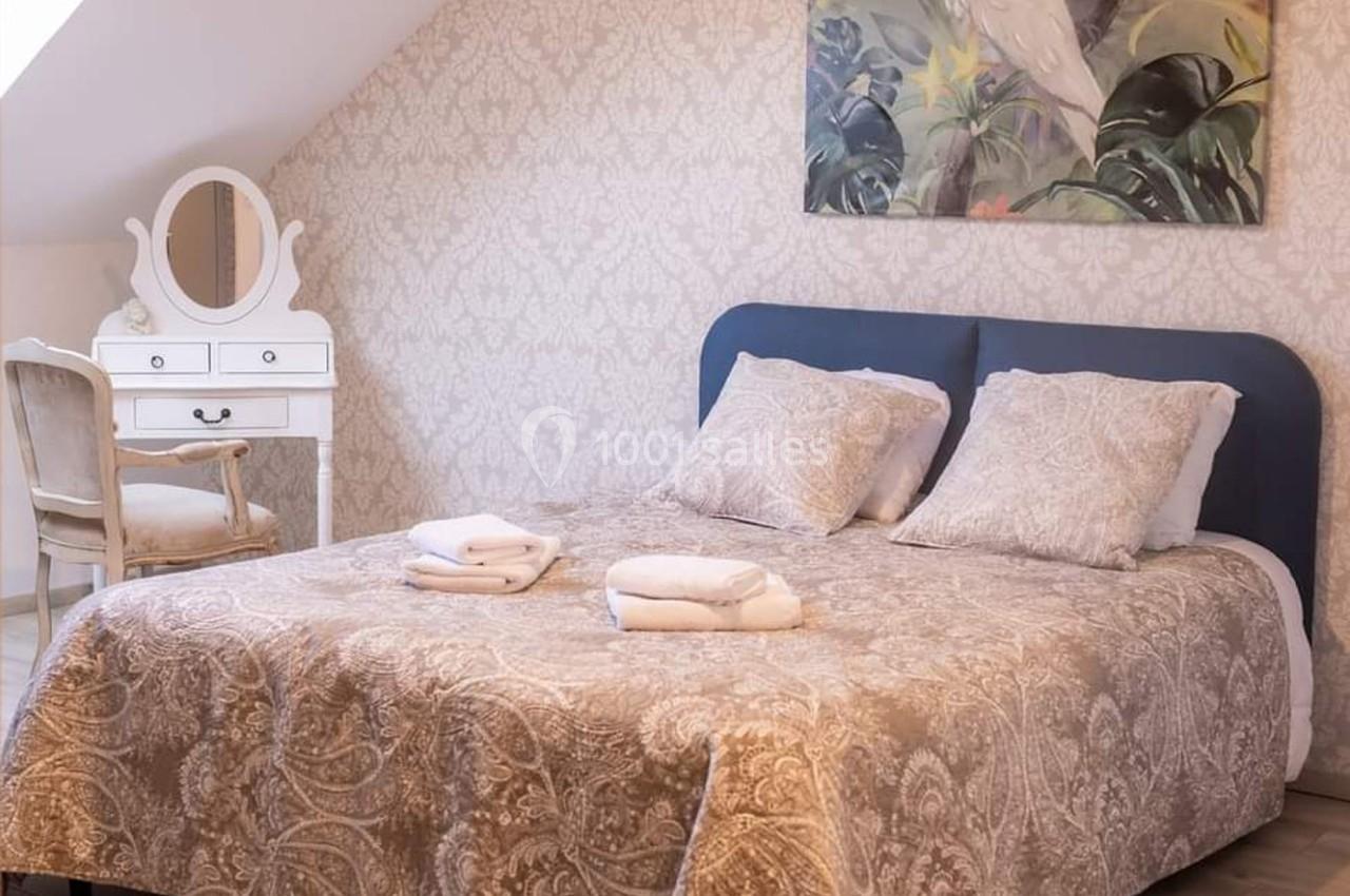 Chambre lumineuse avec un lit double, une coiffeuse blanche et une décoration murale florale.