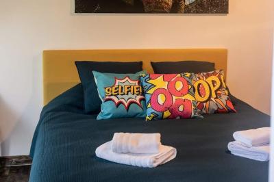 Lit simple avec une tête de lit en bois, couvert d'une couverture à motifs tropicaux, dans une chambre lumineuse.