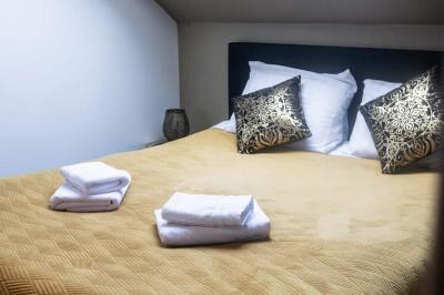 Lit simple avec une tête de lit en bois, couvert d'une couverture à motifs tropicaux, dans une chambre lumineuse.