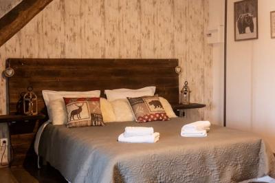 Lit simple avec une tête de lit en bois, couvert d'une couverture à motifs tropicaux, dans une chambre lumineuse.