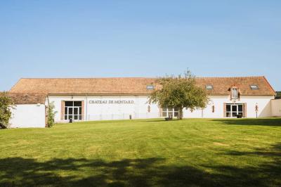 Lit simple avec une tête de lit en bois, couvert d'une couverture à motifs tropicaux, dans une chambre lumineuse.