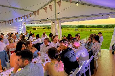 Un homme assis dans un hélicoptère au sol, souriant, avec un coucher de soleil et un champ en arrière-plan.