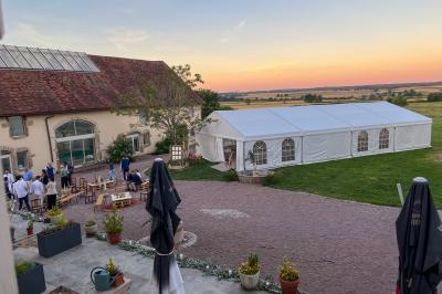 Un homme assis dans un hélicoptère au sol, souriant, avec un coucher de soleil et un champ en arrière-plan.