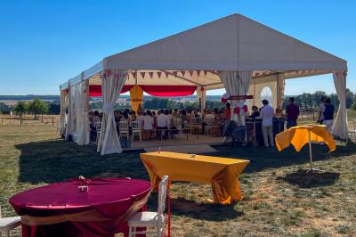 Un homme assis dans un hélicoptère au sol, souriant, avec un coucher de soleil et un champ en arrière-plan.