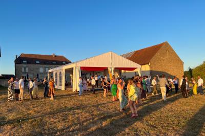 Un homme assis dans un hélicoptère au sol, souriant, avec un coucher de soleil et un champ en arrière-plan.