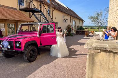 Un homme assis dans un hélicoptère au sol, souriant, avec un coucher de soleil et un champ en arrière-plan.
