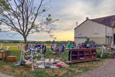 Un homme assis dans un hélicoptère au sol, souriant, avec un coucher de soleil et un champ en arrière-plan.