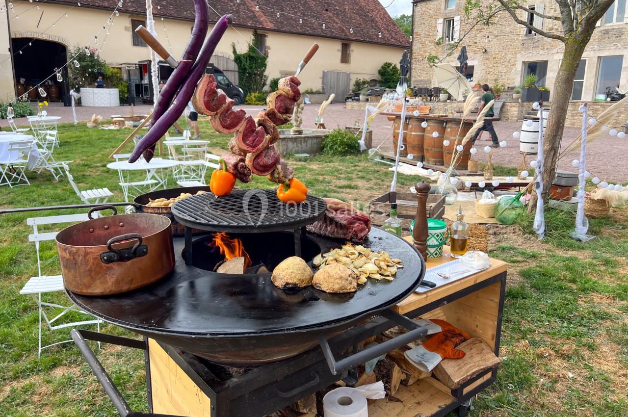 Barbecue en plein air avec brochettes de viande, légumes grillés et pains cuisant sur une plancha ronde dans un jardin…
