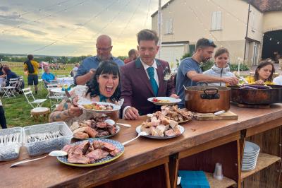 Un homme assis dans un hélicoptère au sol, souriant, avec un coucher de soleil et un champ en arrière-plan.