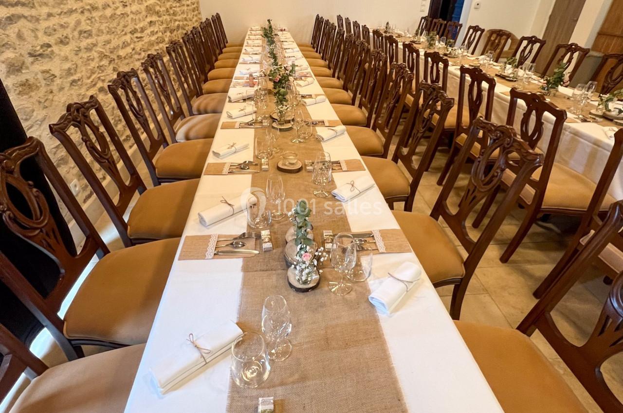 Grande table de banquet décorée avec des chemins de table en toile de jute, vaisselle élégante et chaises en bois.