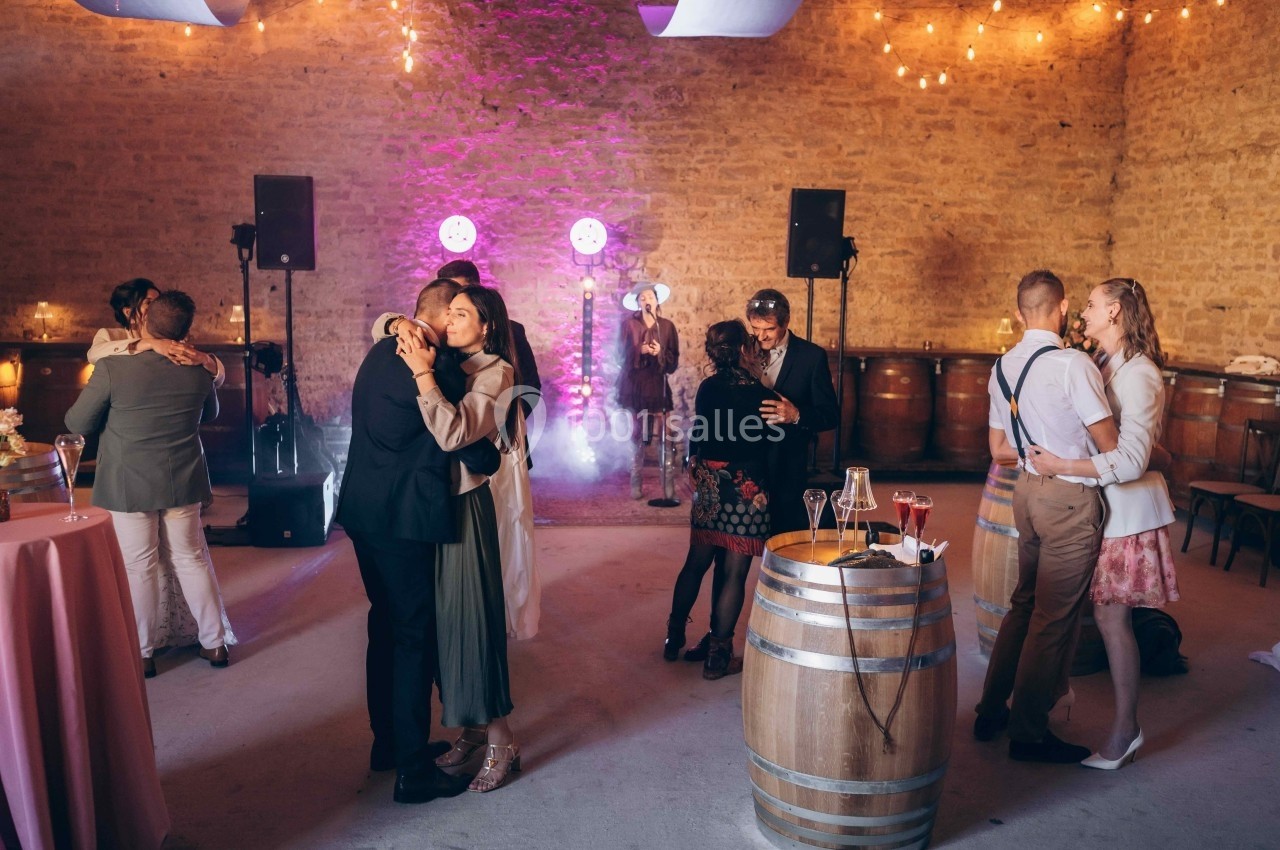 Location salle Souhey (Côte-d'Or) - La Maison de Souhey #58 Des couples dansent dans une salle en pierre éclairée par des guirlandes lumineuses et des projecteurs colorés.