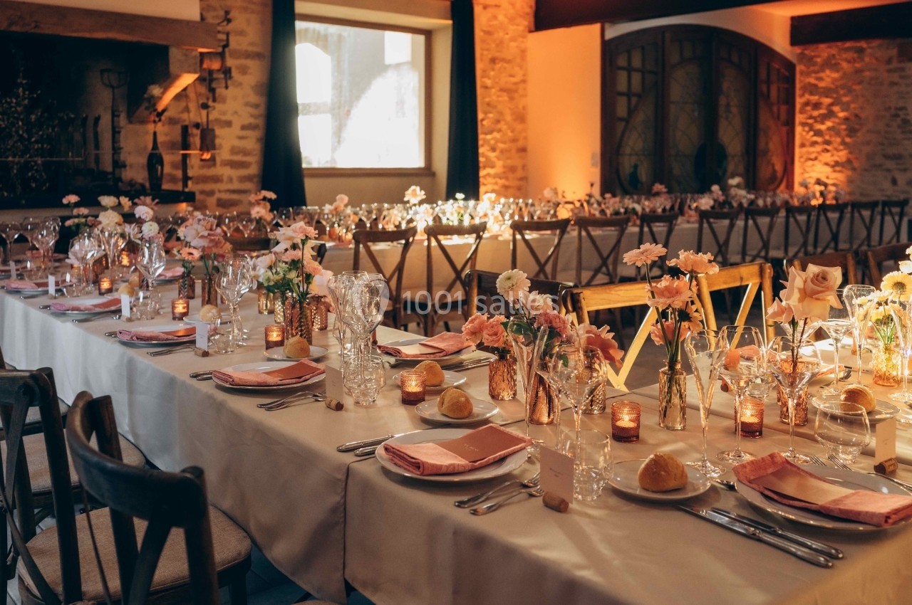 Location salle Souhey (Côte-d'Or) - La Maison de Souhey #38 Salle de réception décorée avec des tables alignées, nappes blanches, fleurs pastel et bougies allumées.