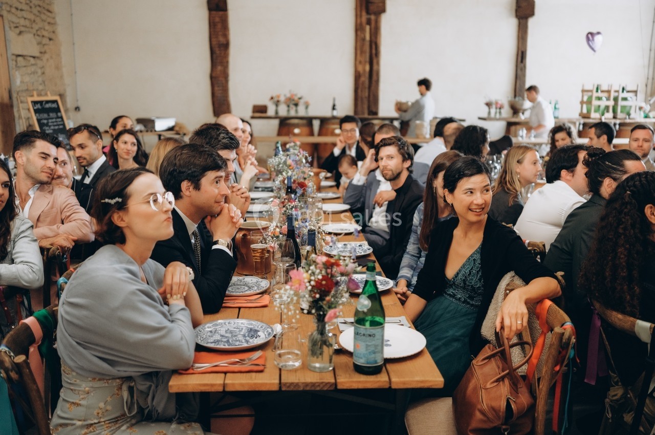 Location salle Souhey (Côte-d'Or) - La Maison de Souhey #67 Des convives assis à une longue table décorée, lors d'un repas dans une salle au style rustique.