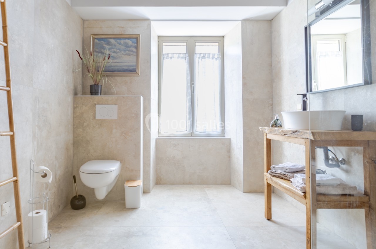 Location salle Souhey (Côte-d'Or) - La Maison de Souhey #45 Salle de bain lumineuse avec toilettes suspendues, vasque sur meuble en bois et fenêtre laissant entrer la lumière naturelle.