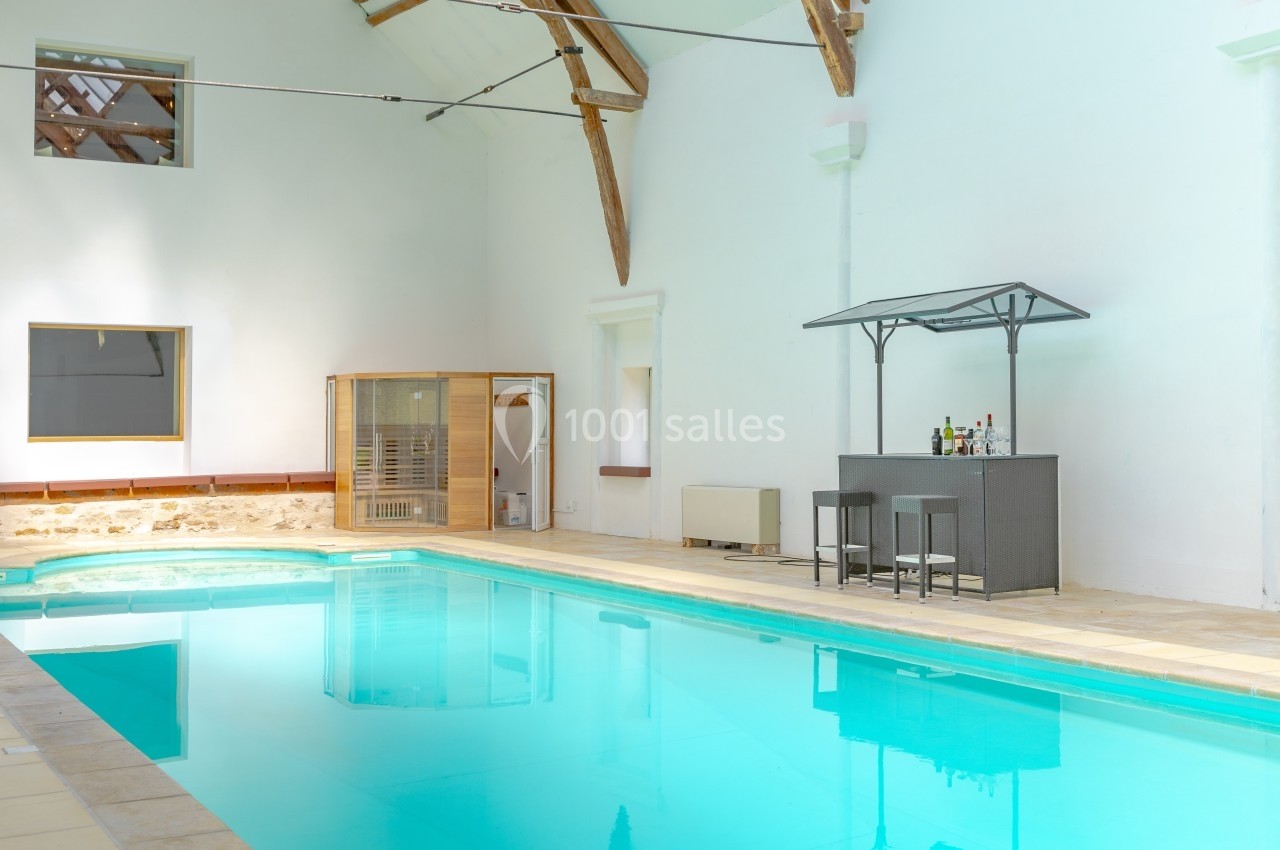 Location salle Souhey (Côte-d'Or) - La Maison de Souhey #8 Piscine intérieure avec bar aménagé et cabine en bois, entourée de murs blancs et éclairée par la lumière naturelle.