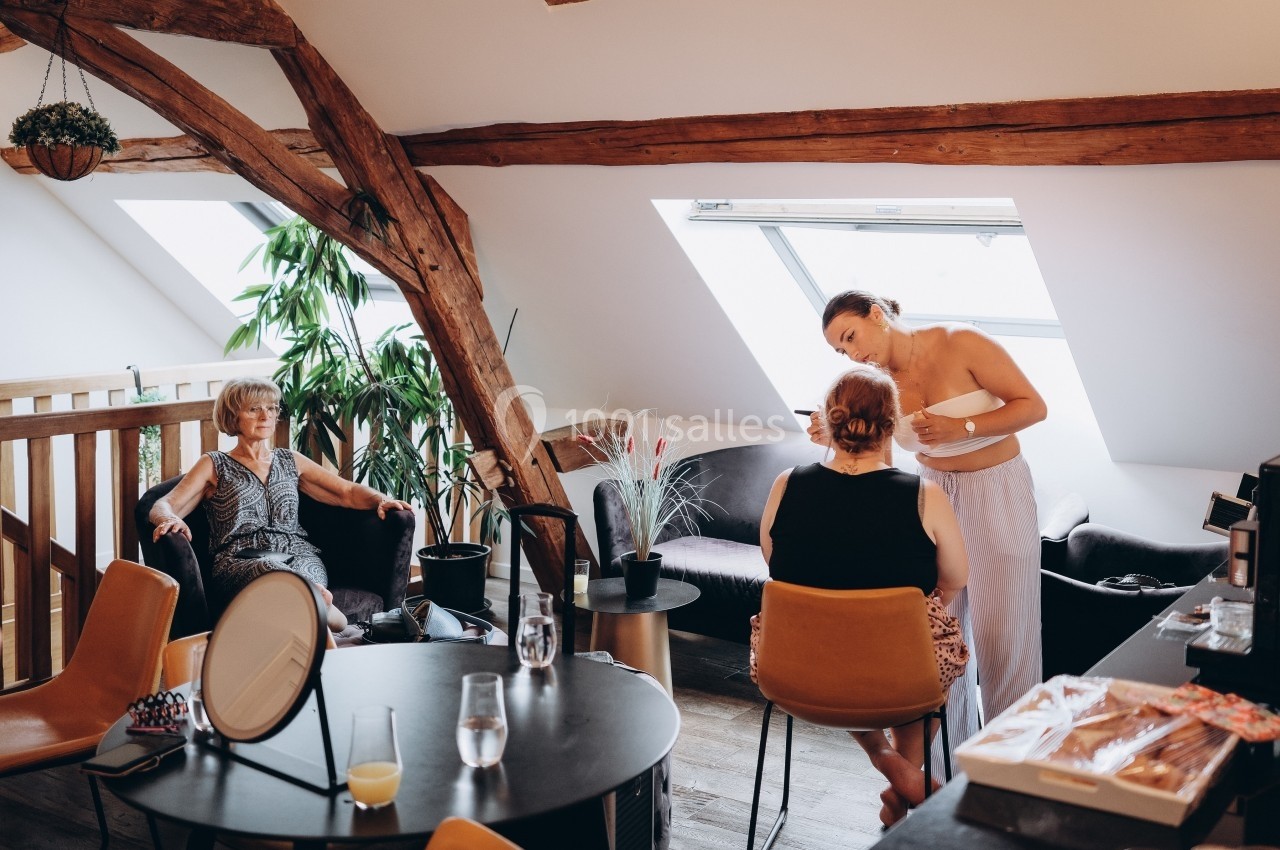 Location salle Souhey (Côte-d'Or) - La Maison de Souhey #70 Deux femmes discutent pendant une séance de maquillage dans un salon lumineux avec poutres apparentes, une autre femme…