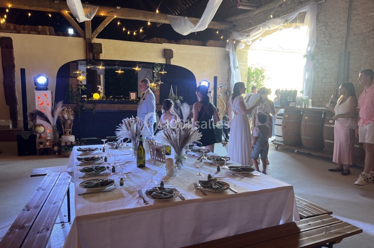 Location salle Souhey (Côte-d'Or) - La Maison de Souhey #93 Salle de réception décorée pour un événement, avec une table dressée et des invités discutant près du bar.