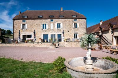 Chambre lumineuse avec lit double, coin salon, salle de bain ouverte avec douche à l'italienne et lavabo moderne.