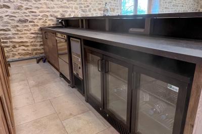 Chambre lumineuse avec lit double, coin salon, salle de bain ouverte avec douche à l'italienne et lavabo moderne.