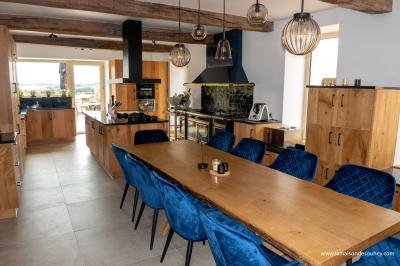 Chambre lumineuse avec lit double, coin salon, salle de bain ouverte avec douche à l'italienne et lavabo moderne.