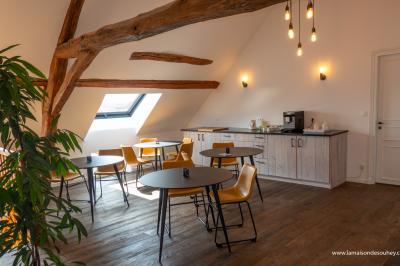 Chambre lumineuse avec lit double, coin salon, salle de bain ouverte avec douche à l'italienne et lavabo moderne.