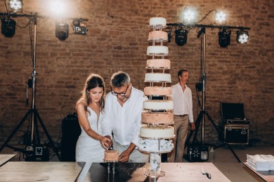 Des invités assis à des tables dans une tente décorée, profitant d'un repas avec vue sur un paysage champêtre au coucher du…