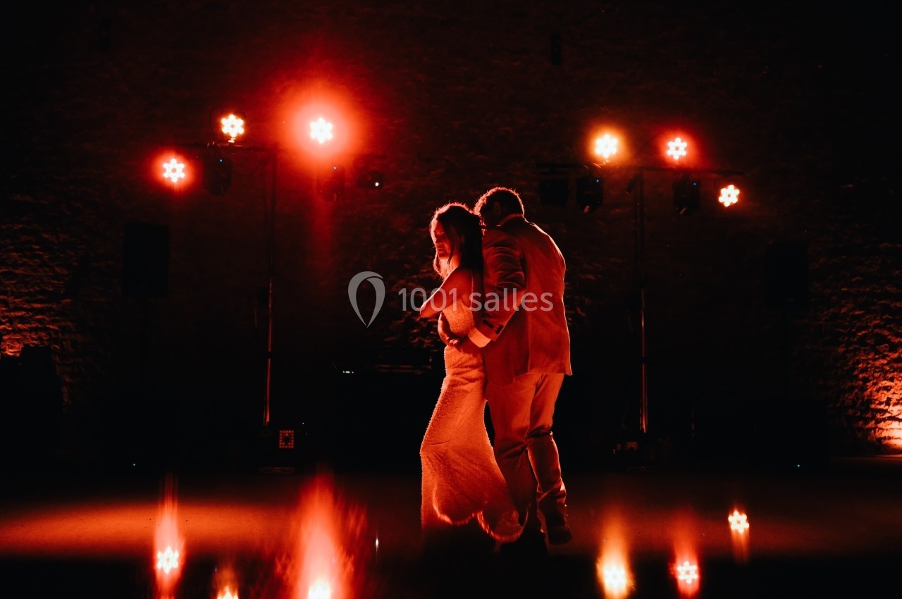 Un couple danse sous des lumières rouges dans une ambiance sombre et chaleureuse.