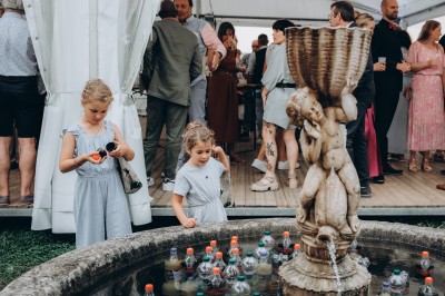 Des invités assis à des tables dans une tente décorée, profitant d'un repas avec vue sur un paysage champêtre au coucher du…