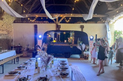 Des invités assis à des tables dans une tente décorée, profitant d'un repas avec vue sur un paysage champêtre au coucher du…
