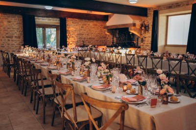 Des invités assis à des tables dans une tente décorée, profitant d'un repas avec vue sur un paysage champêtre au coucher du…