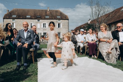 Des invités assis à des tables dans une tente décorée, profitant d'un repas avec vue sur un paysage champêtre au coucher du…