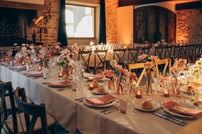 Des invités assis à des tables dans une tente décorée, profitant d'un repas avec vue sur un paysage champêtre au coucher du…