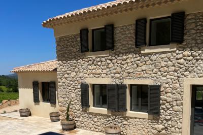 Bouteille de vin rosé entourée de verres vides sur une table en bois, avec une plante en arrière-plan.